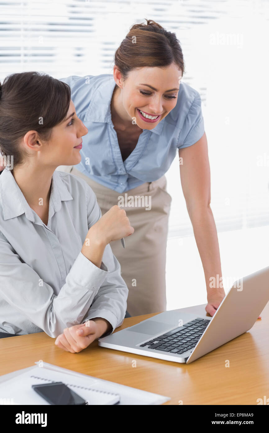 Smiling businesswomen working together with laptop Stock Photo - Alamy
