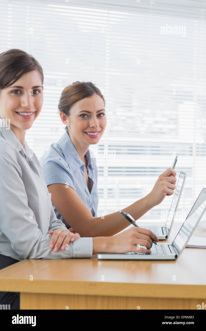 Smiling businesswomen working on their laptops portrait Stock Photo - Alamy