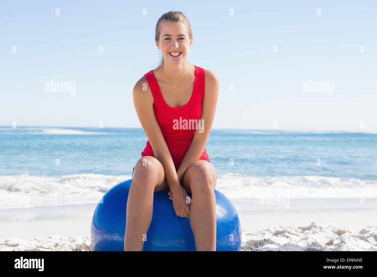 Fit young woman sitting on exercise ball smiling at camera Stock Photo ...