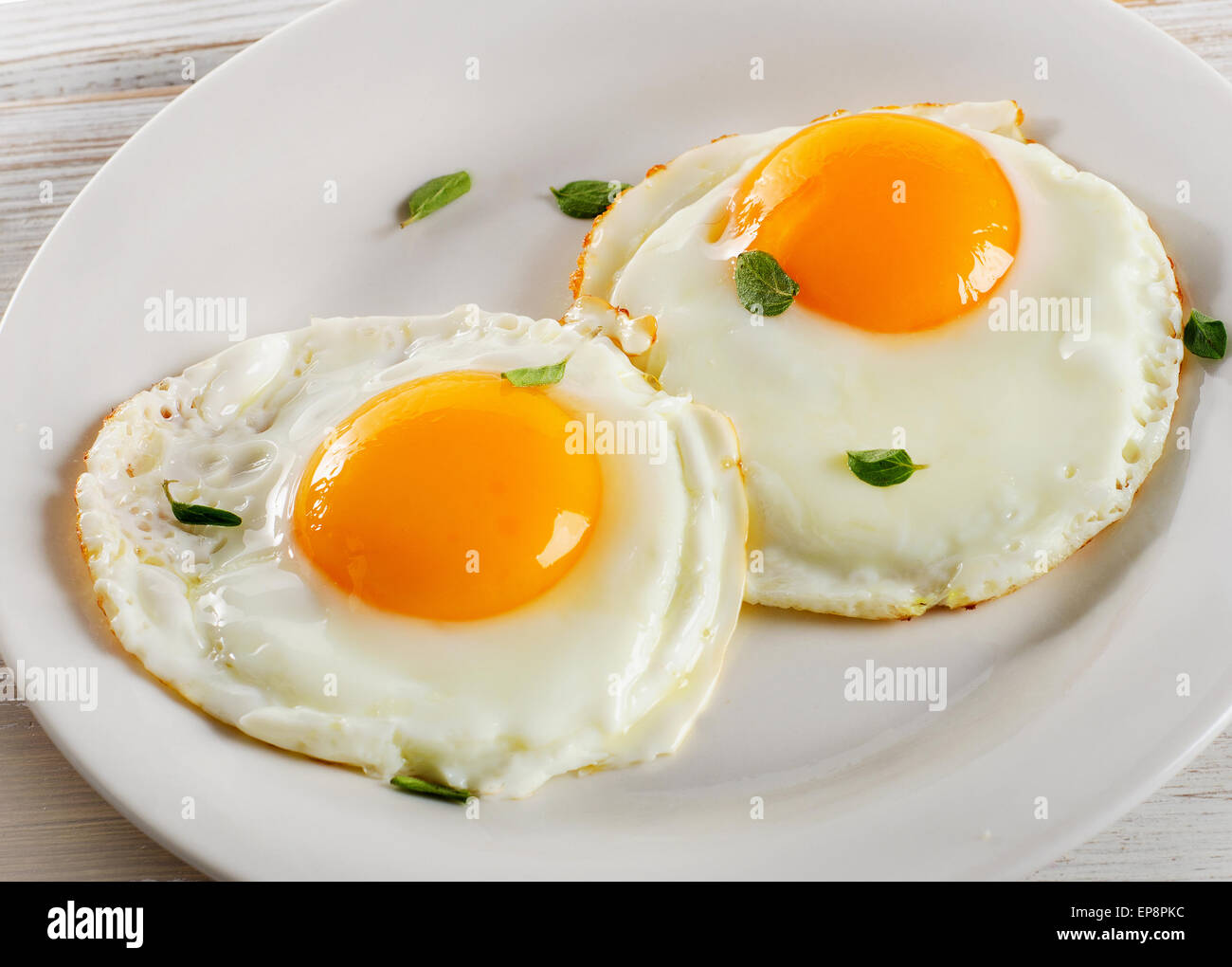 Two fried eggs on white plate for healthy breakfast Stock Photo - Alamy
