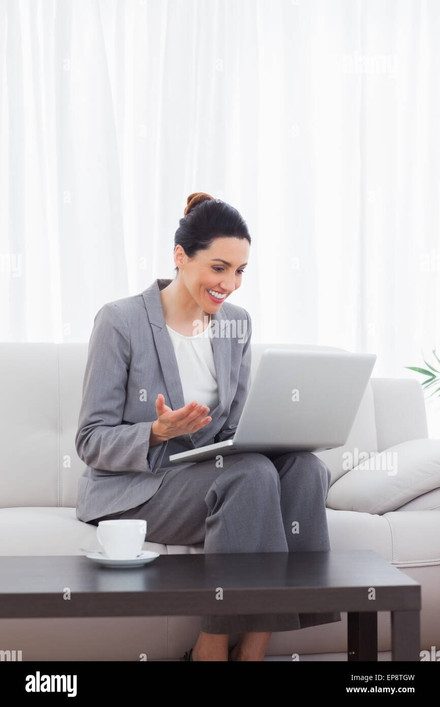 Happy busineswoman sitting on sofa using laptop Stock Photo - Alamy
