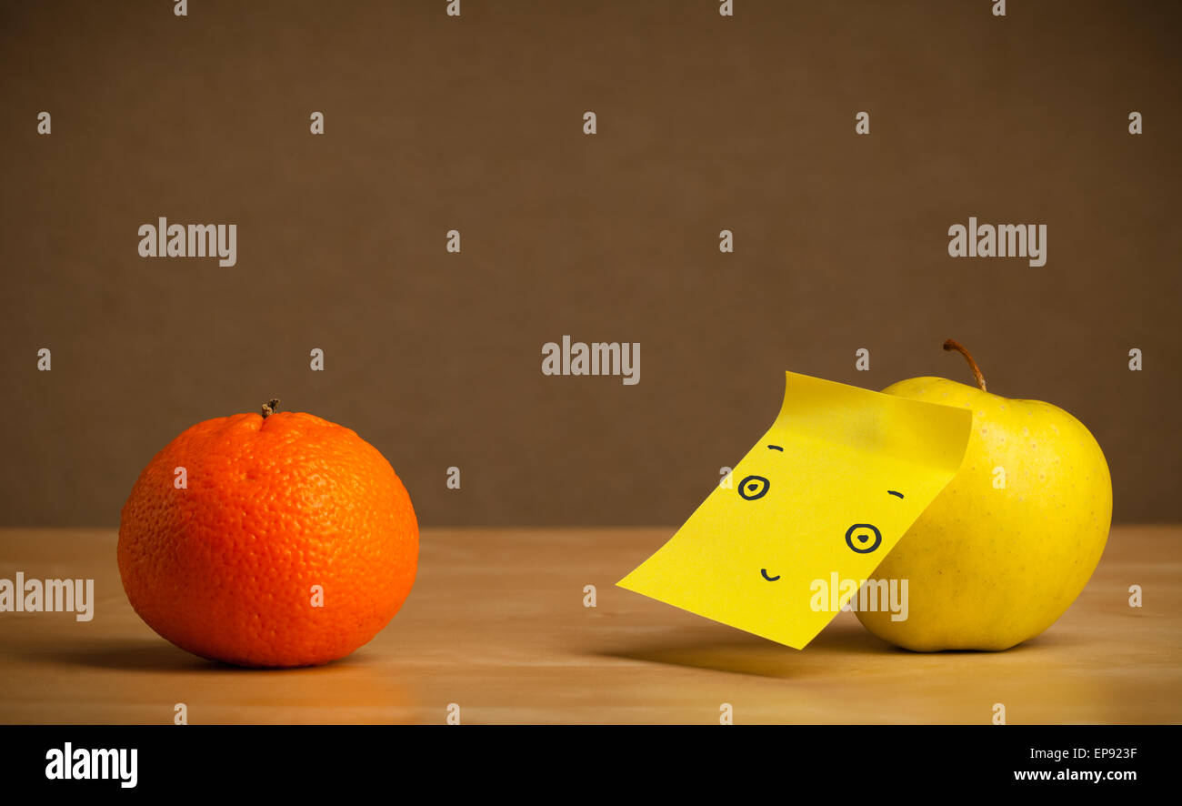 Apple with post-it note looking at orange Stock Photo - Alamy