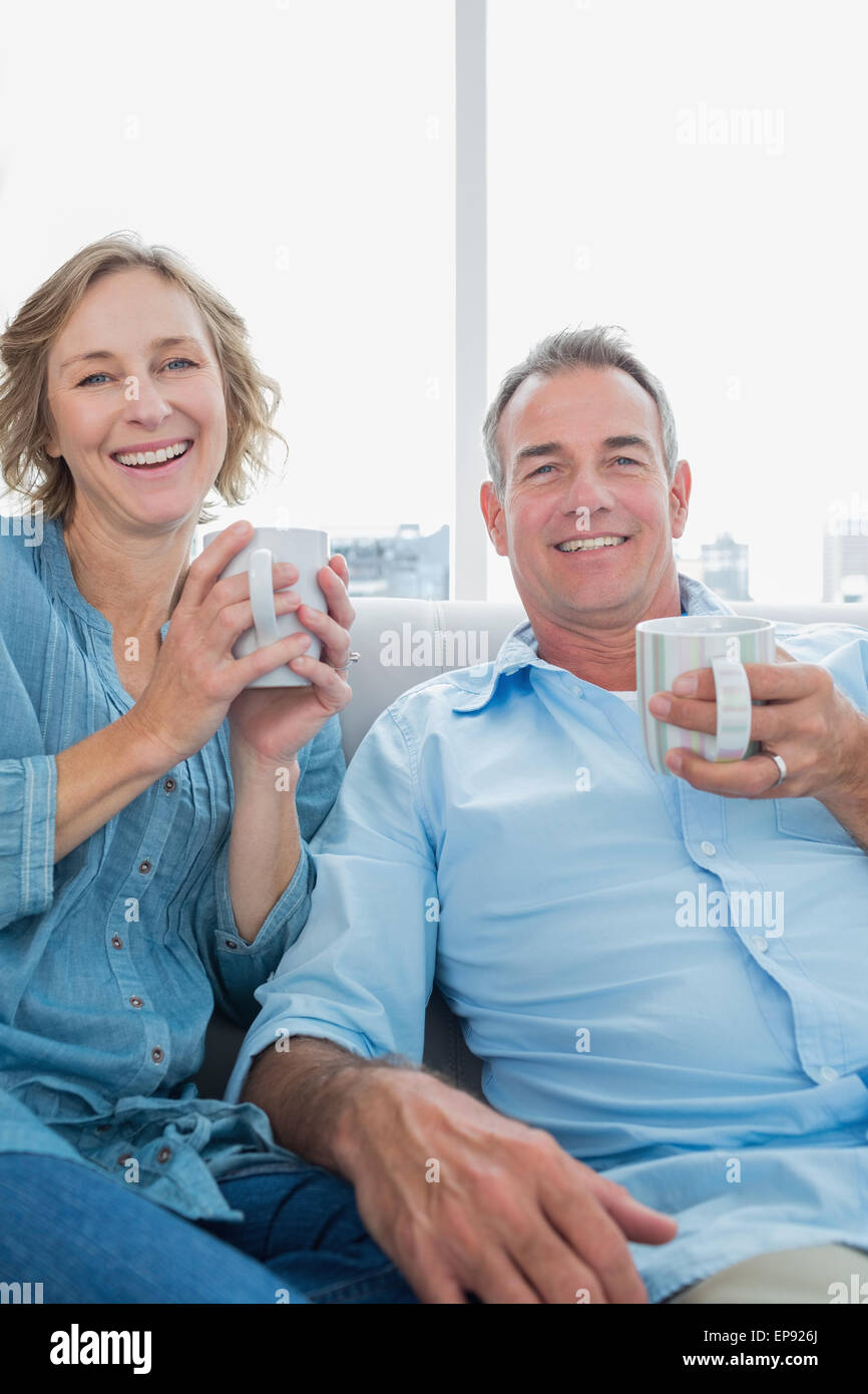 Happy middle aged couple sitting on the couch having coffee Stock Photo ...