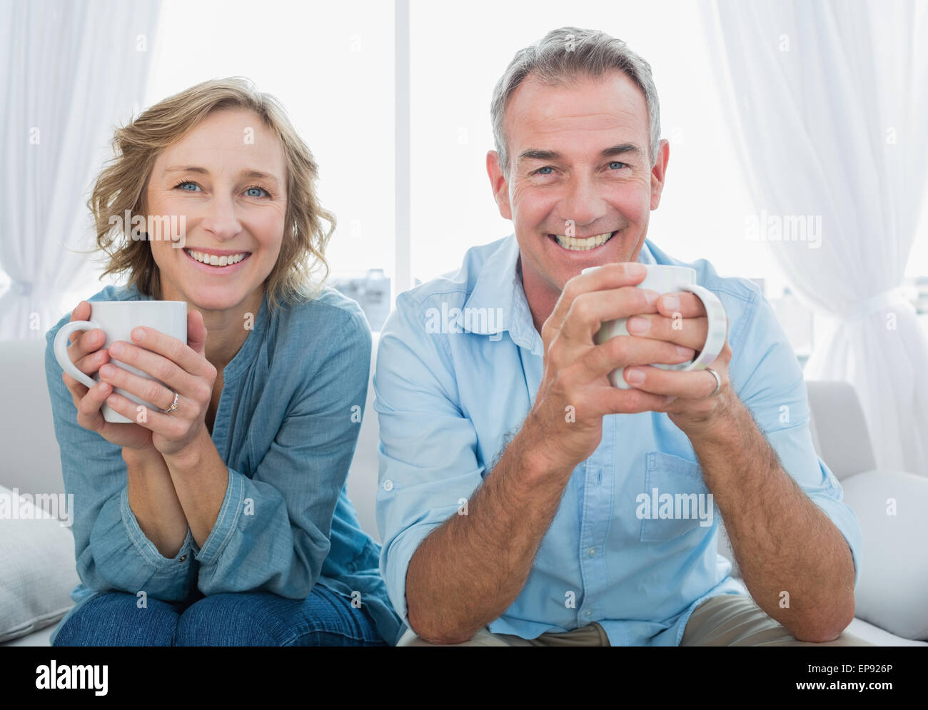 Smiling middle aged couple sitting on the couch having coffee Stock ...