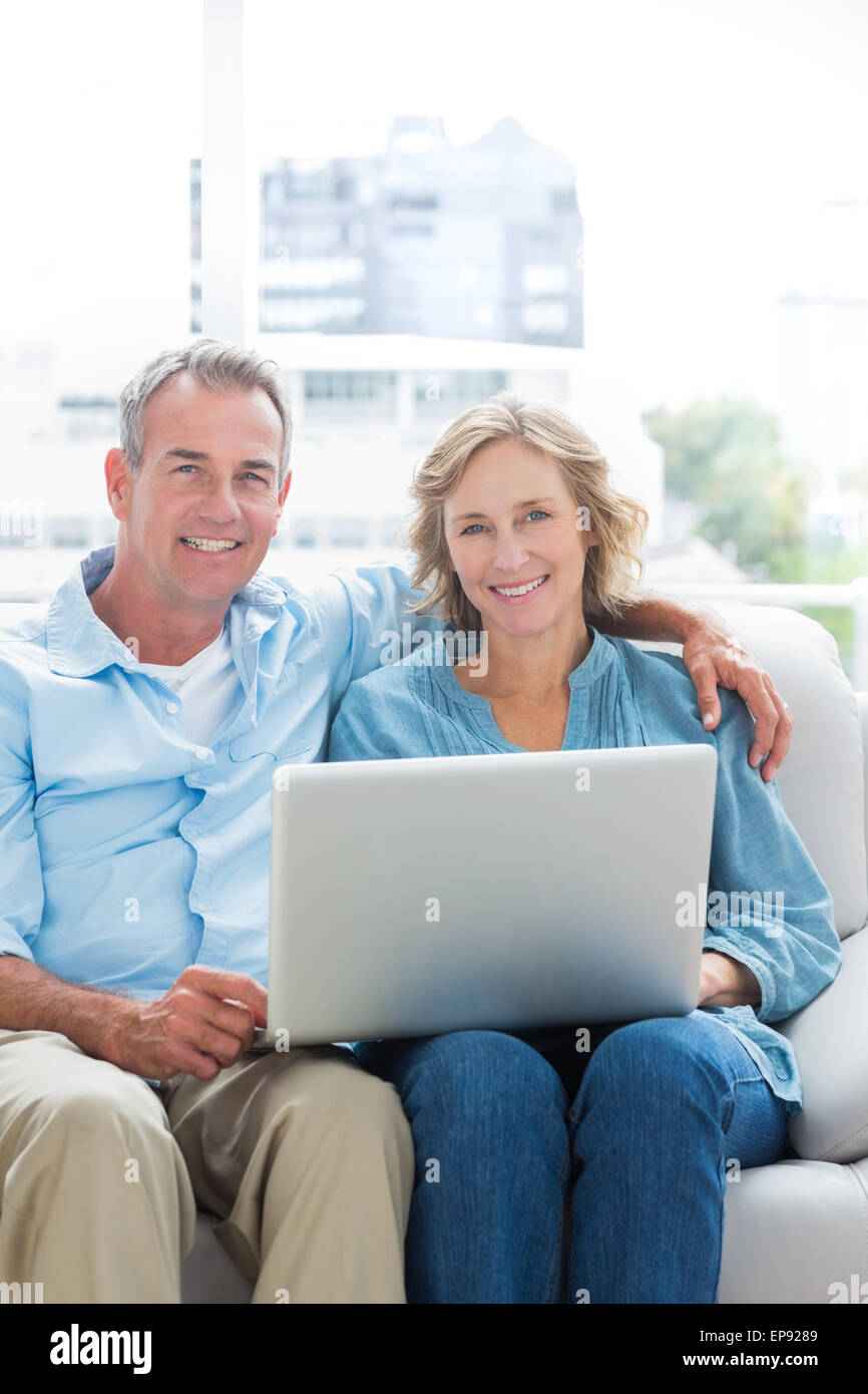 Smiling couple relaxing on their couch using the laptop Stock Photo - Alamy