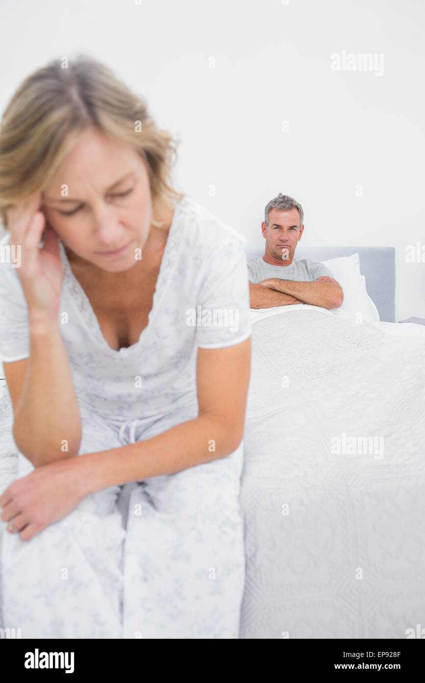 Annoyed Couple Sitting On Opposite Ends Of Bed After A Fight Stock