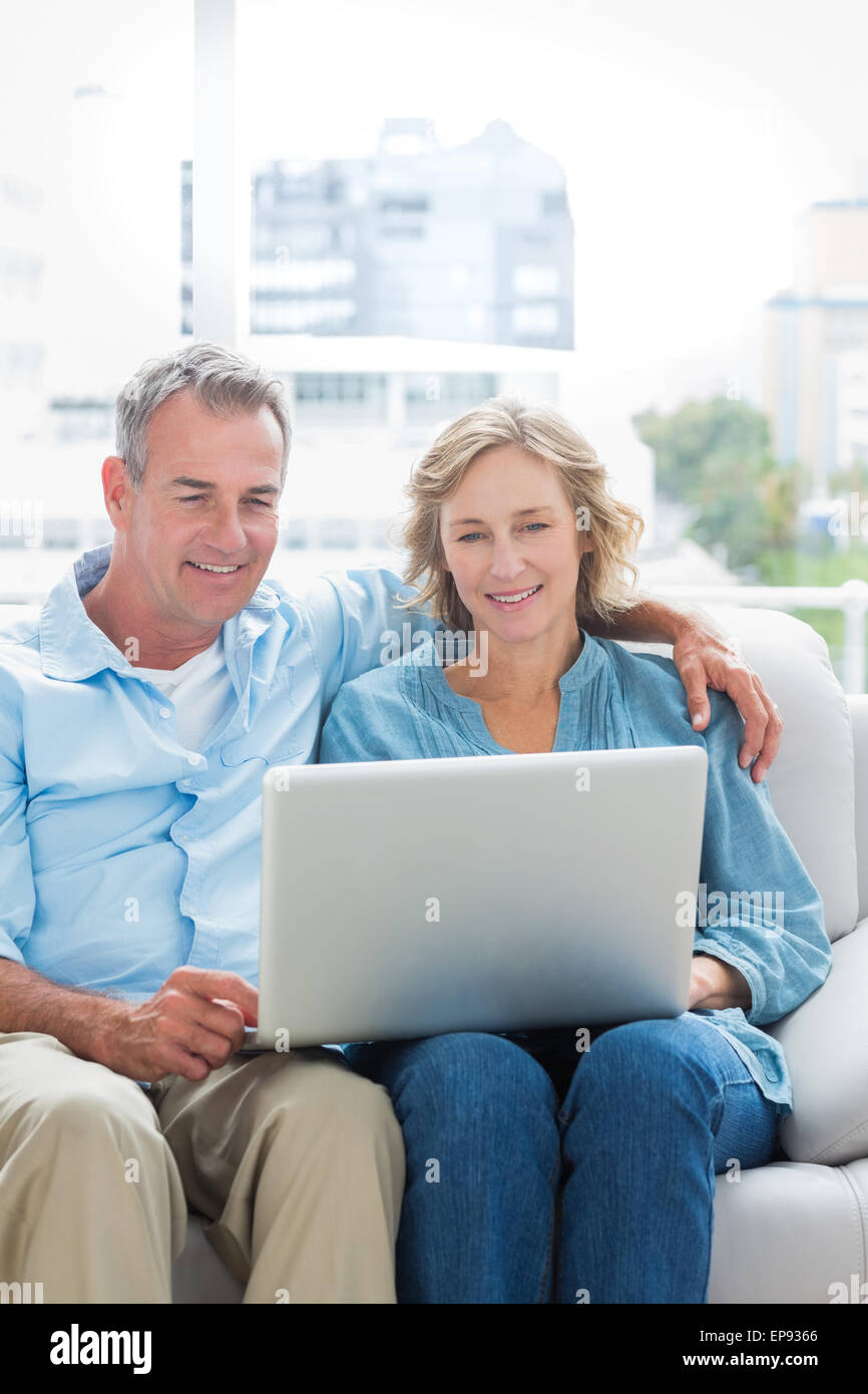 Smiling couple sitting on their couch using the laptop Stock Photo - Alamy