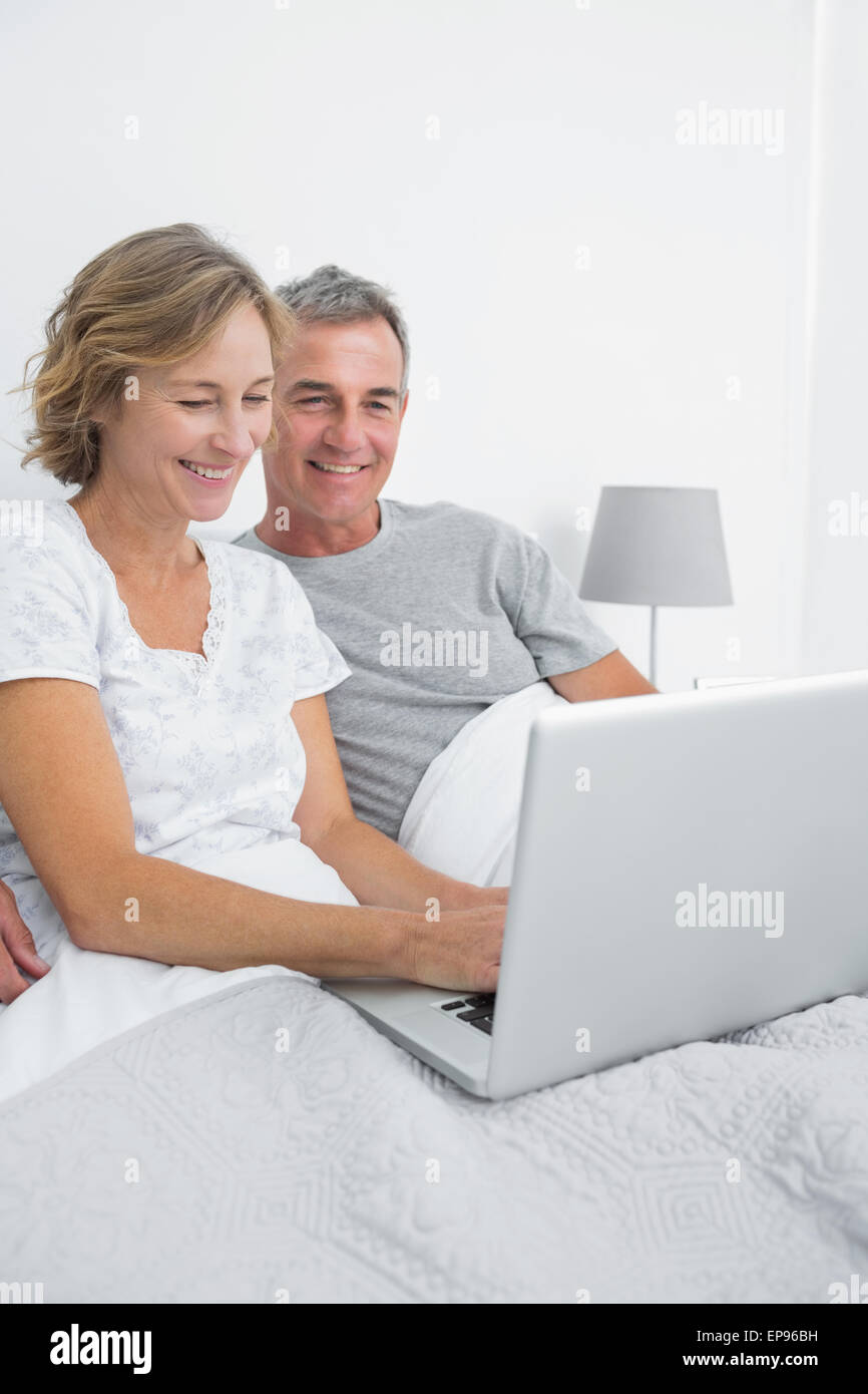 Cheerful couple using their laptop together in bed Stock Photo - Alamy