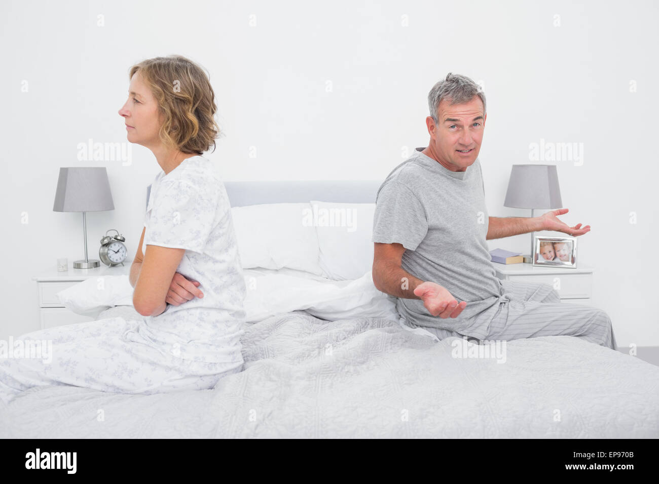Couple sitting on different sides of bed having a dispute Stock Photo ...