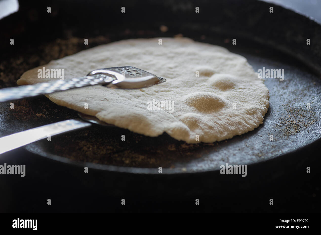 Floury tortillas being turned while cooking in hot griddle pan Stock