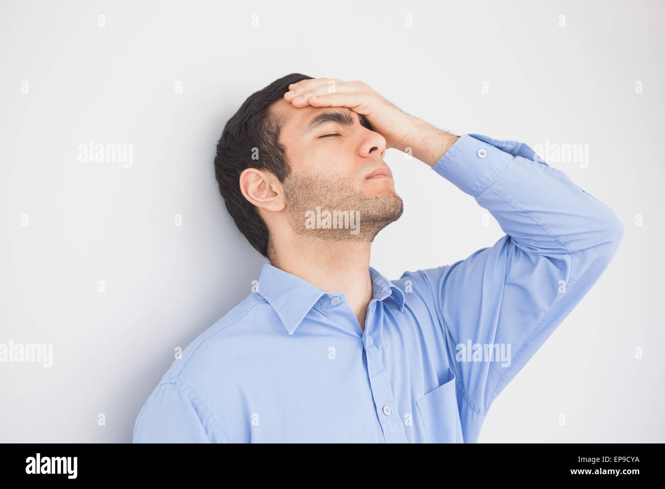 Irritated man with hand on forehead leaning against a wall Stock Photo ...
