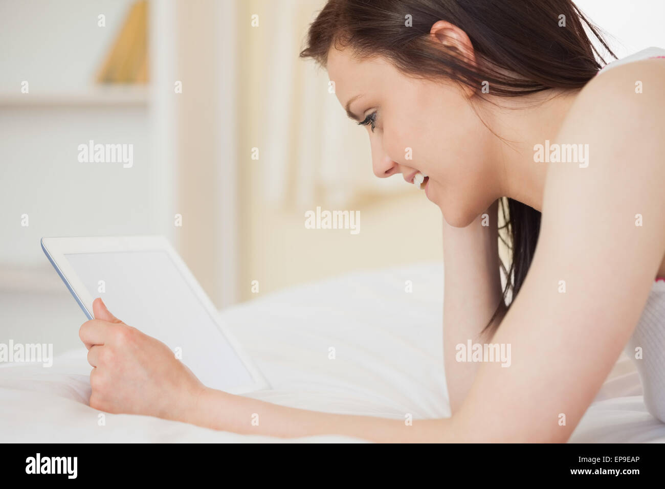 Smiling girl using a digital tablet lying on her bed Stock Photo - Alamy