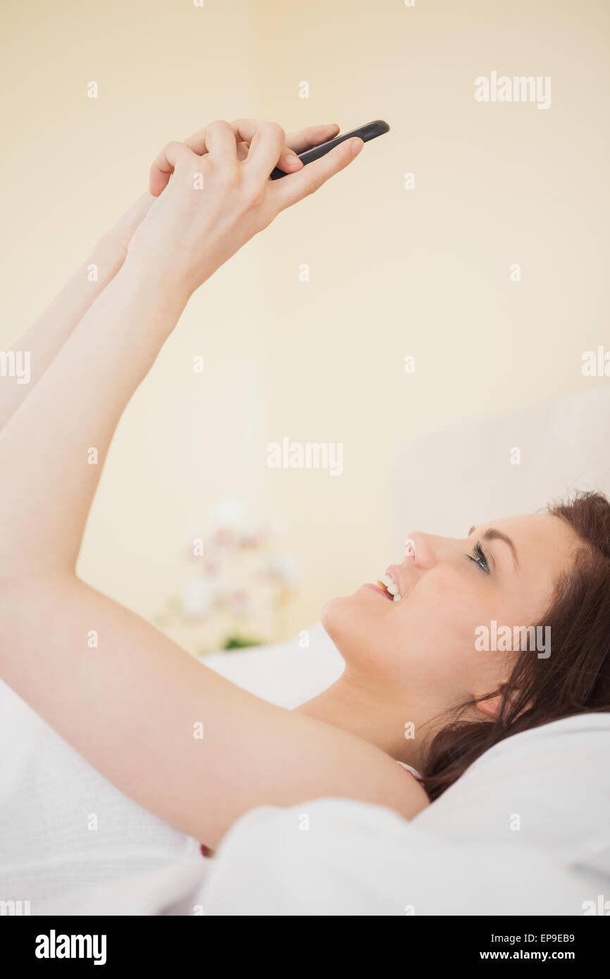 Happy girl using a mobile phone lying on a bed Stock Photo - Alamy