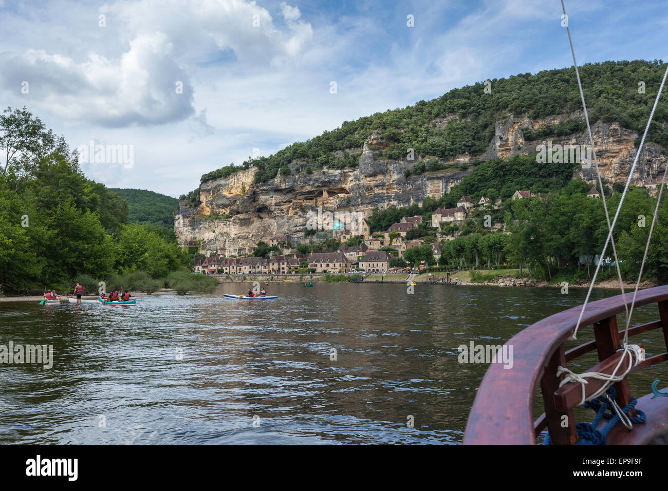 Canoeing on the river Dordogne at La Roque-Gageac, Dordogne, France with the rocky cliffs and village in the background against a blue sky with clouds Stock Photo