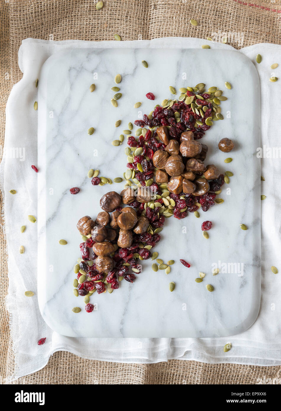 Roast chestnuts, cranberries and seeds on a marble chopping board. Stock Photo