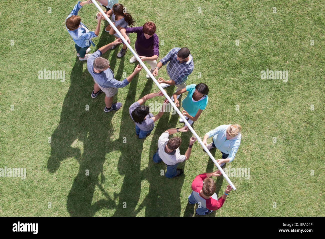 team balancing pole fingertip sunny field Stock Photo