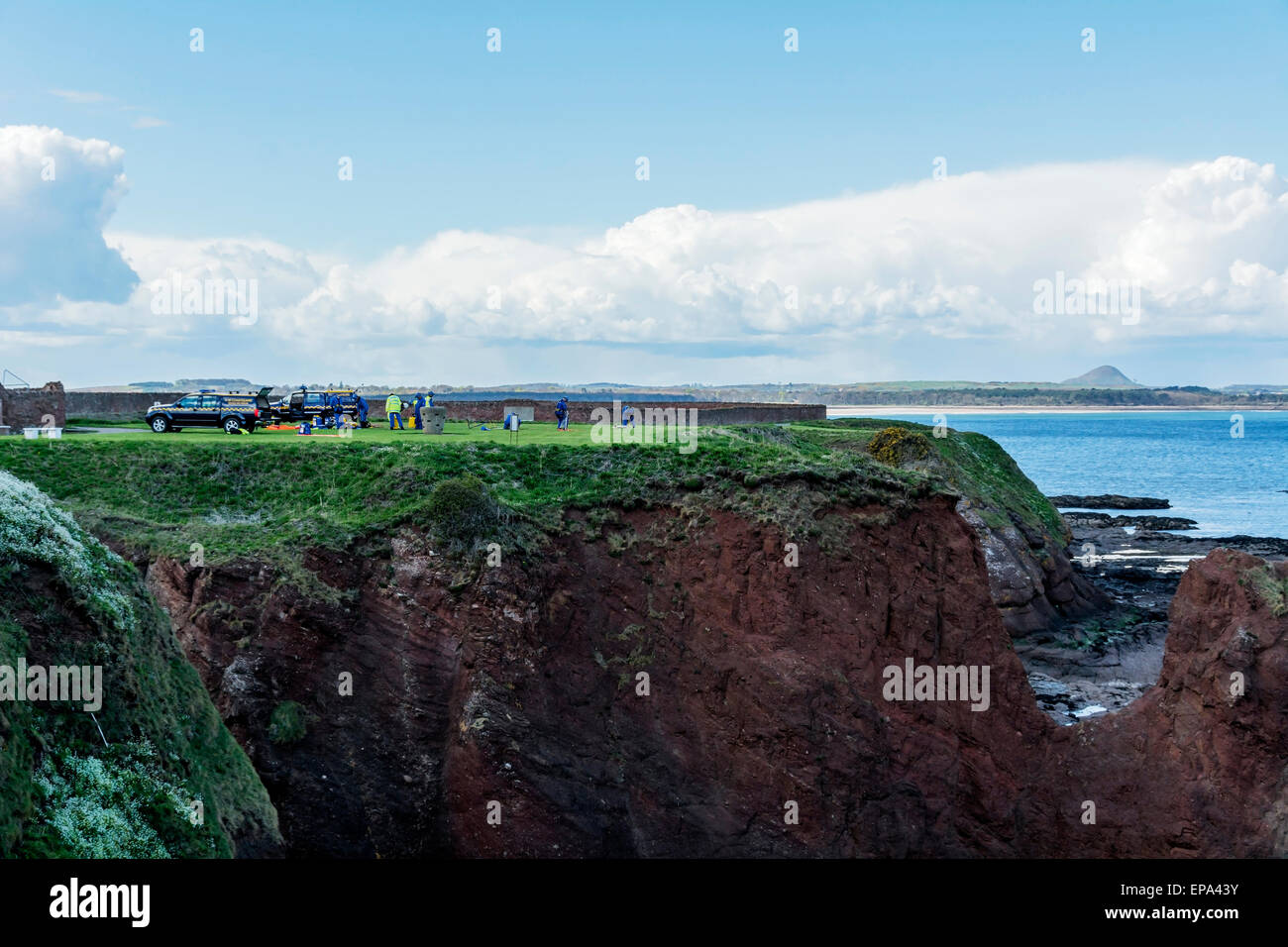 Coastguard emergency cliff rescue workers training on the cliffs at Dunbar, Scotland - with North Berwick Law in background. Stock Photo