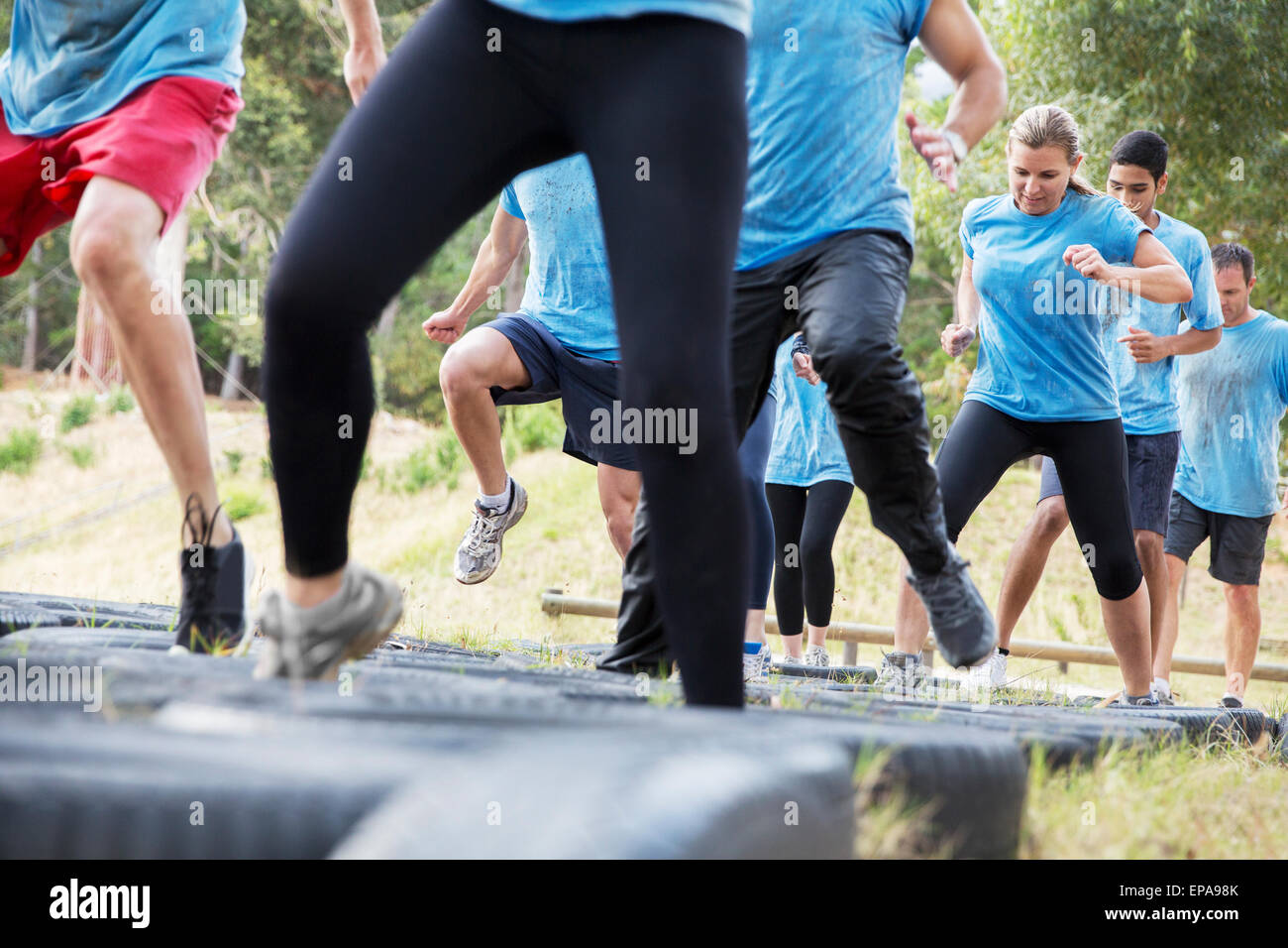 people jumping tire boot camp obstacle course Stock Photo