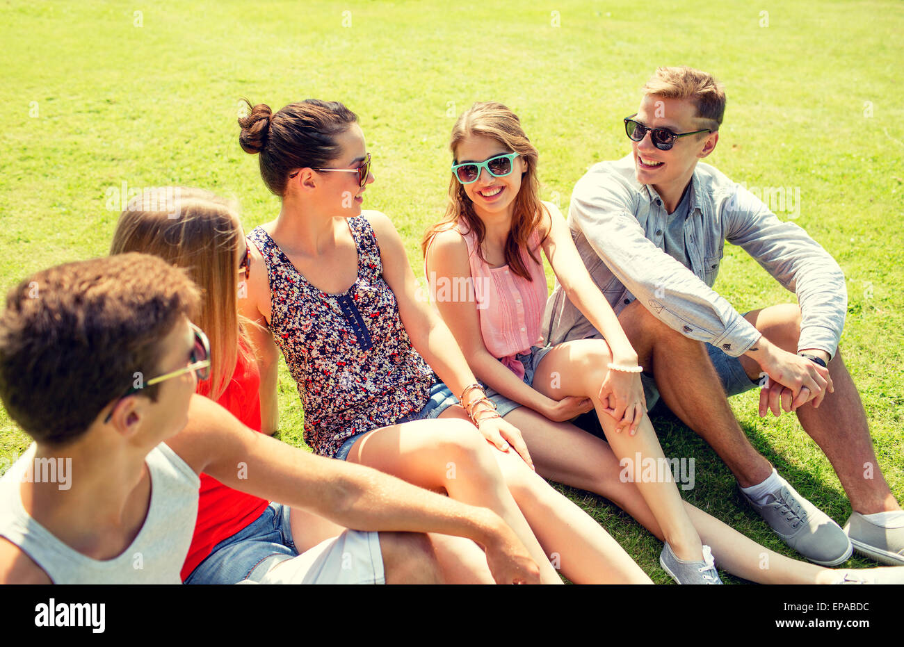 group of smiling friends outdoors sitting in park Stock Photo - Alamy