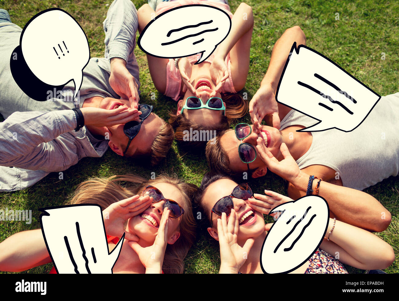 group of smiling friends lying on grass outdoors Stock Photo