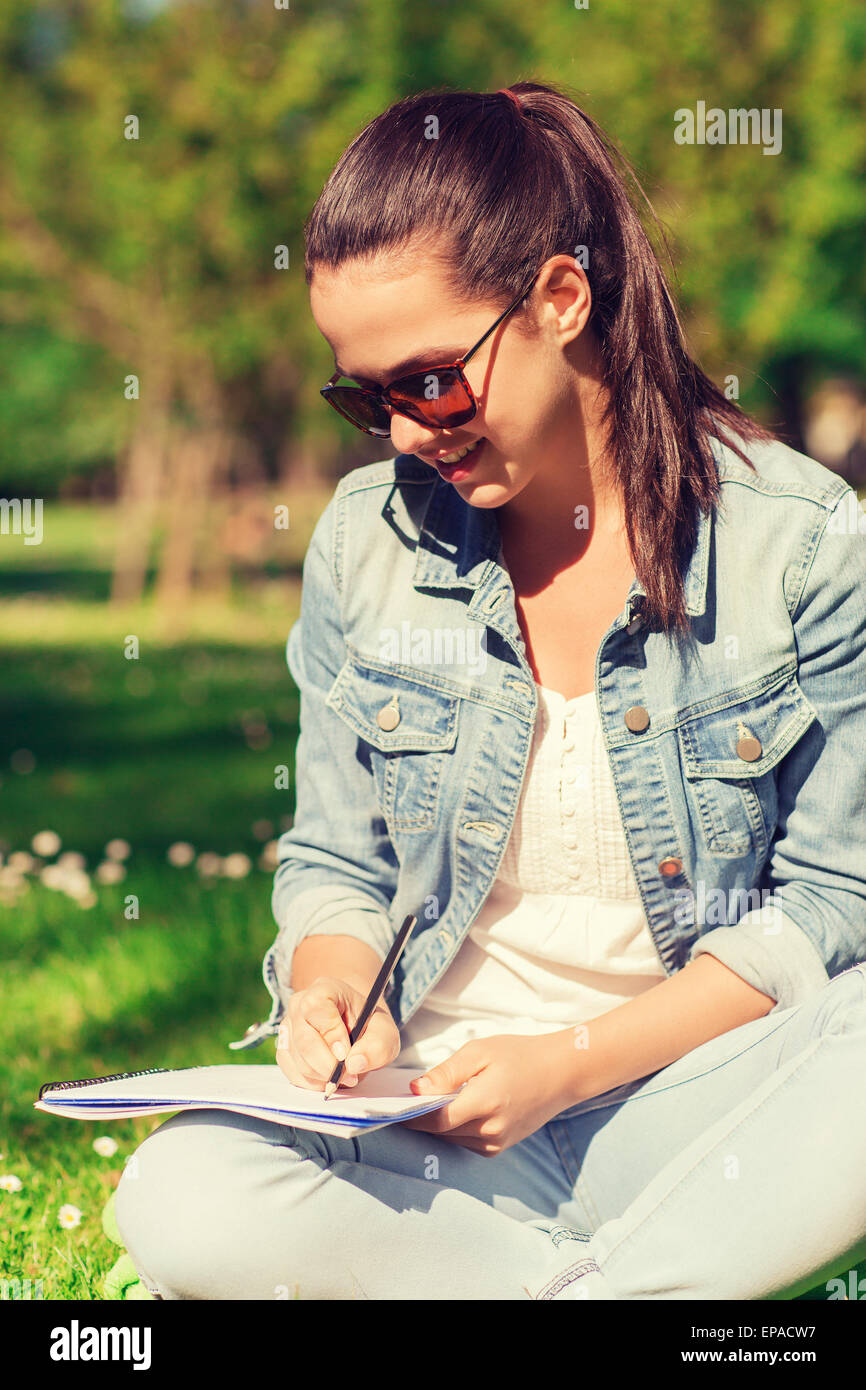 smiling young girl with notebook writing in park Stock Photo - Alamy