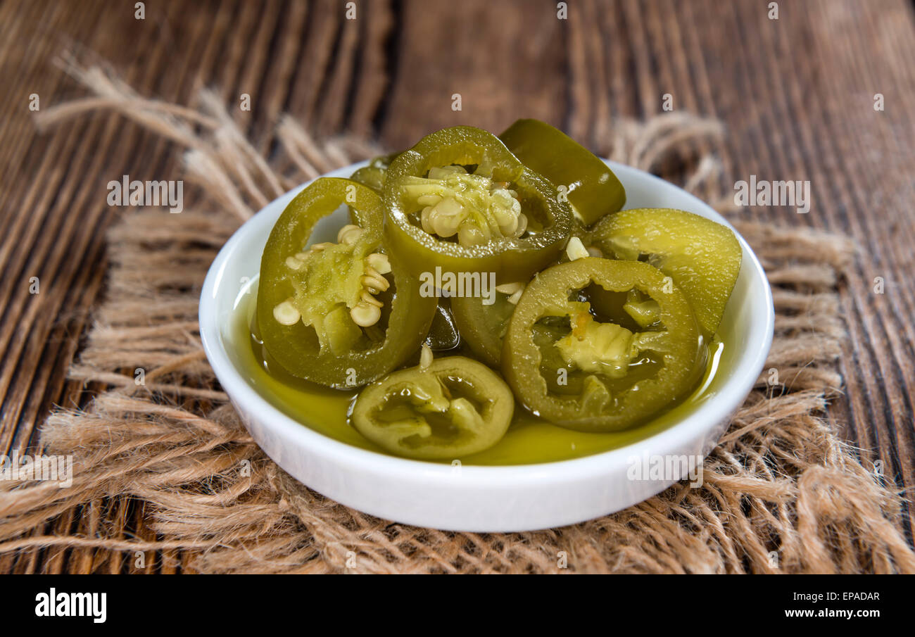Portion of Jalapenos (preserved) on rustic wooden background Stock Photo