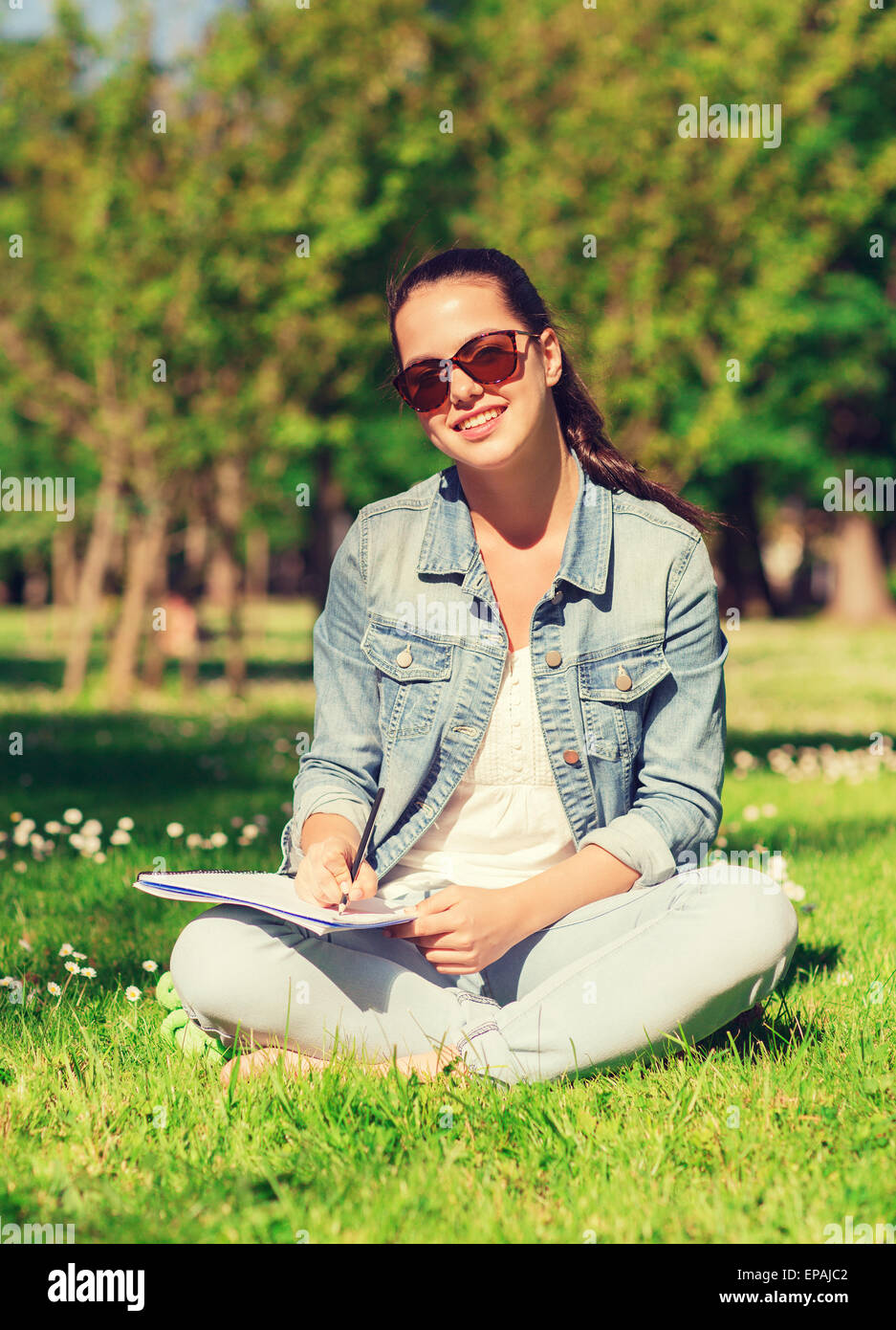 smiling young girl with notebook writing in park Stock Photo - Alamy