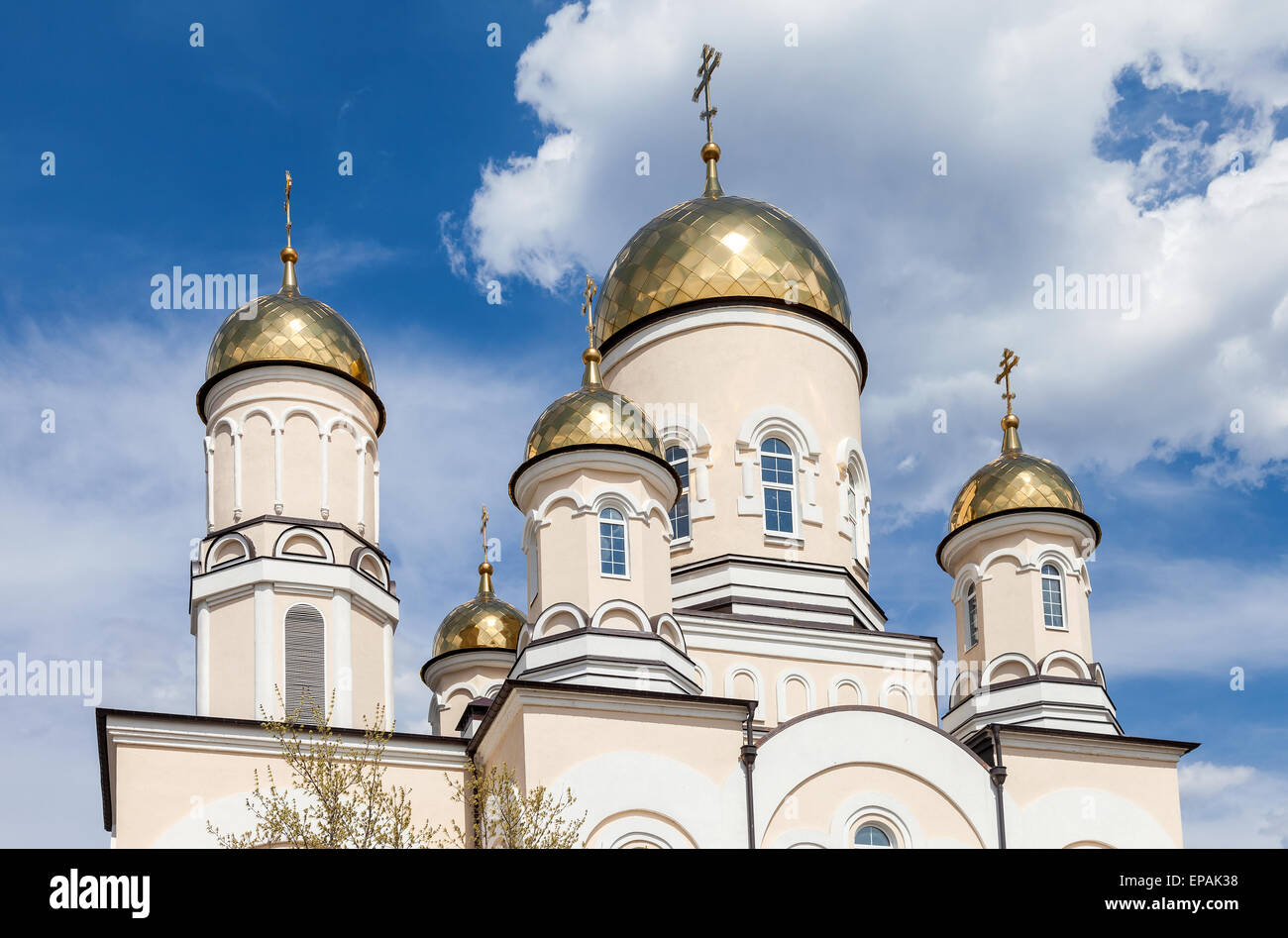 Golden domes of Russian orthodox church with cross against blue sky Stock Photo