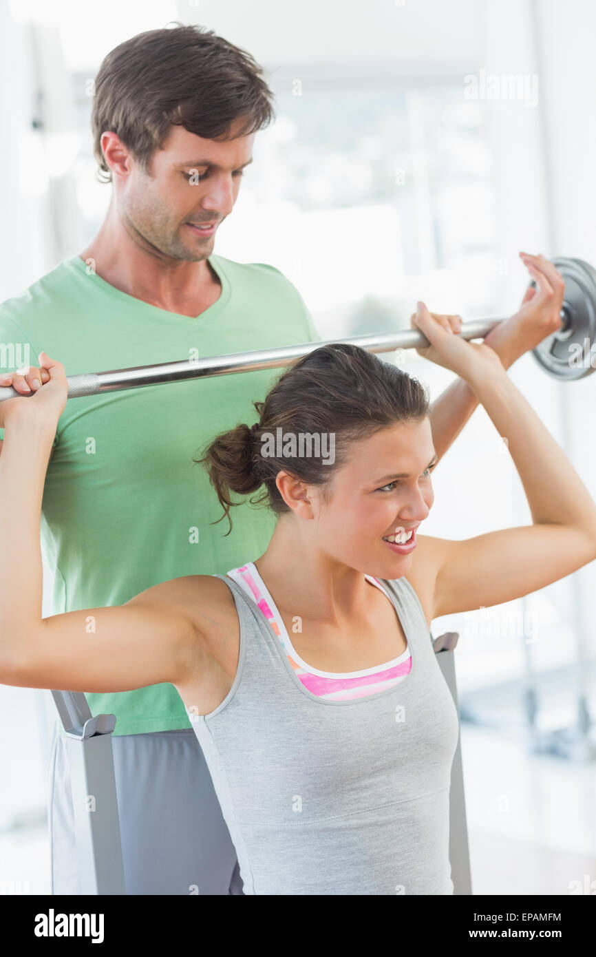 Trainer helping fit woman to lift barbell bench press Stock Photo - Alamy