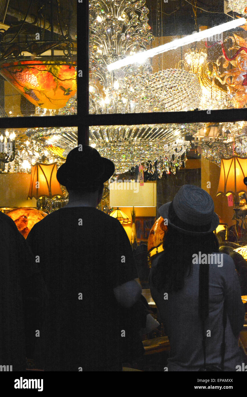 Window shoppers enjoy the night view of a chandelier lighting store display in the French Quarter in New Orleans, LA Stock Photo