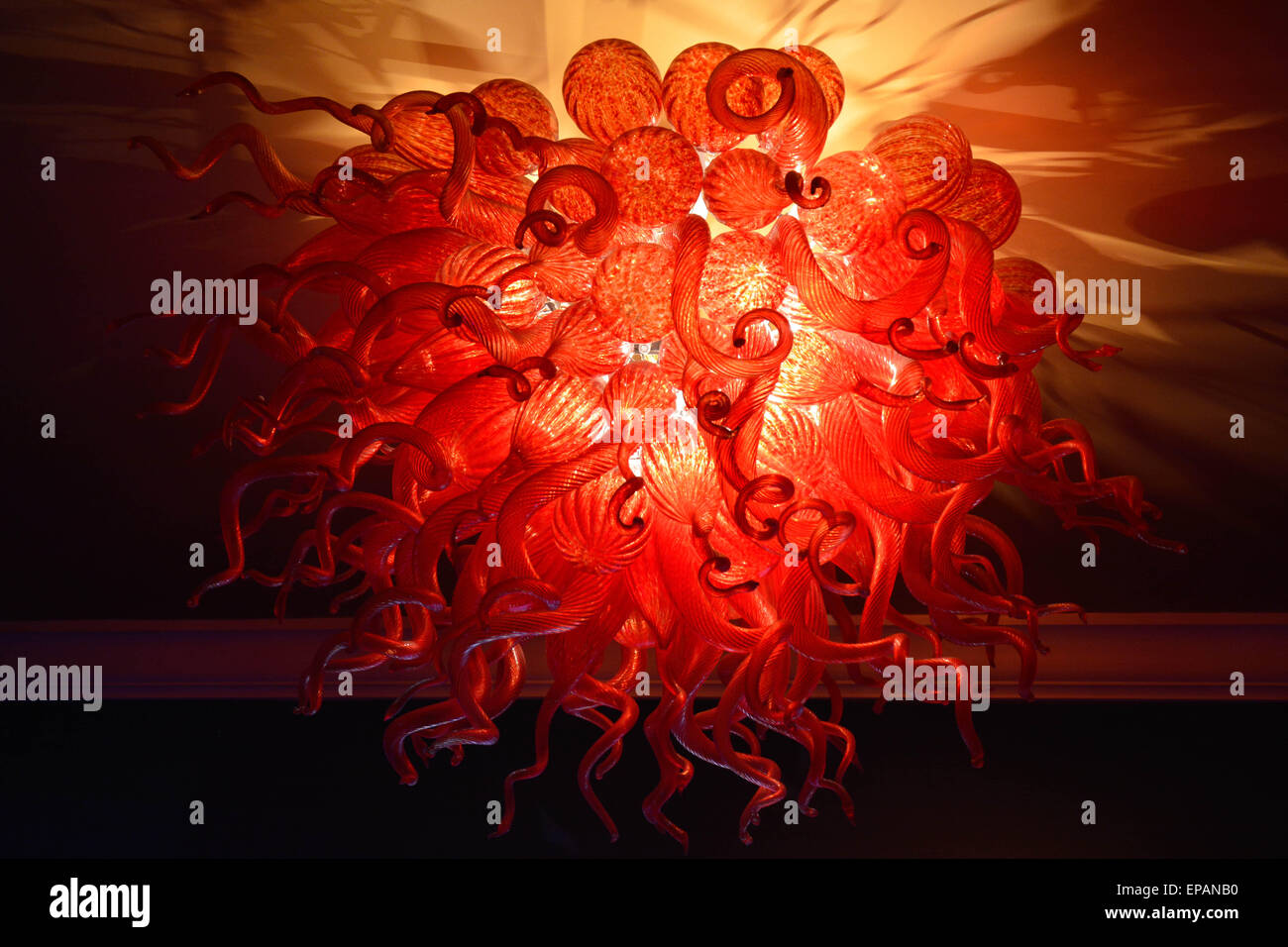 A glowing red hand made art glass chandelier beautifully emits