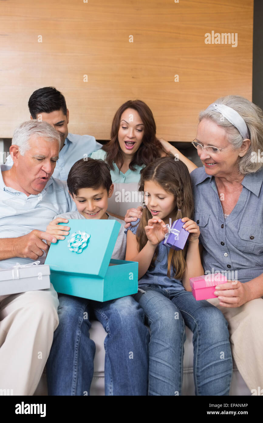 Extended family sitting on sofa with gift boxes in living room Stock