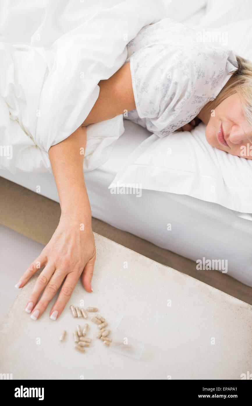 Woman sleeping in bed with pills in foreground Stock Photo
