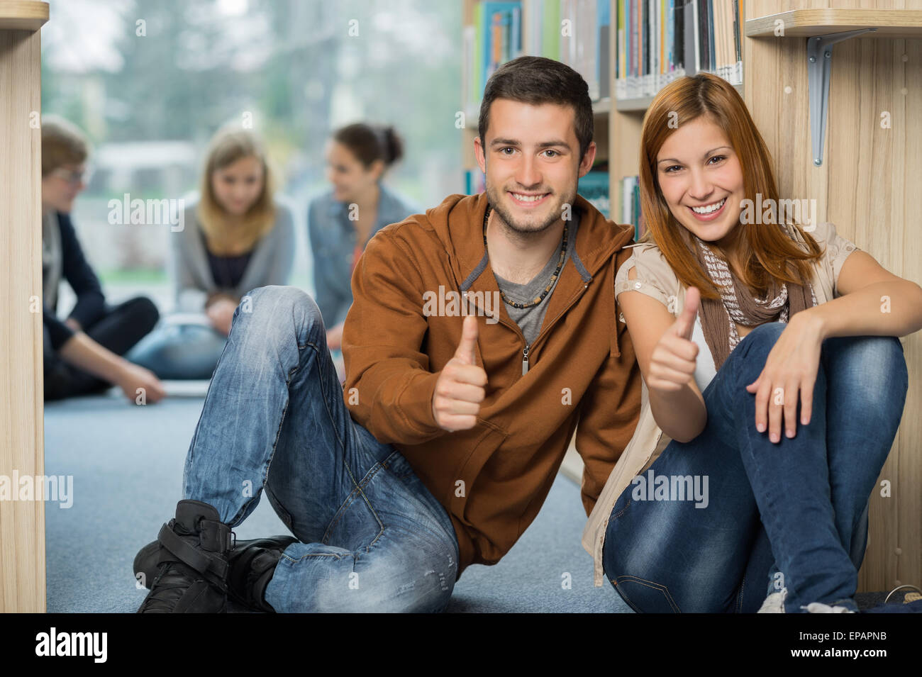 Happy students showing thumb up in library Stock Photo - Alamy
