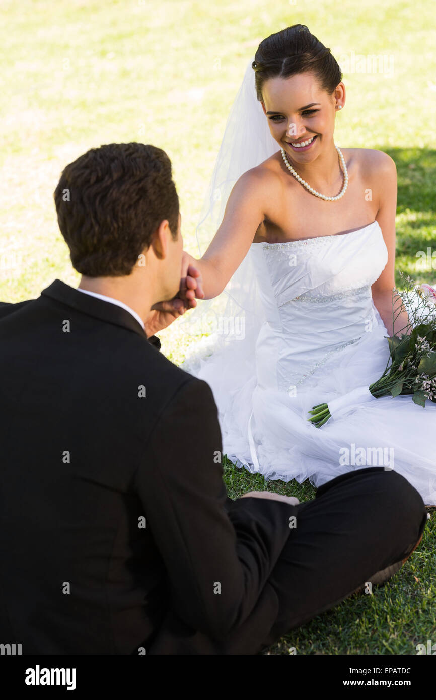 Groom kissing his beautiful bride's hand at park Stock Photo - Alamy