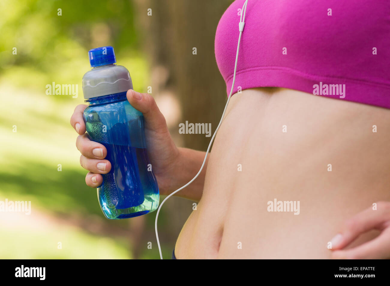Mid section of healthy woman in sports bra with water bottle in park Stock  Photo - Alamy