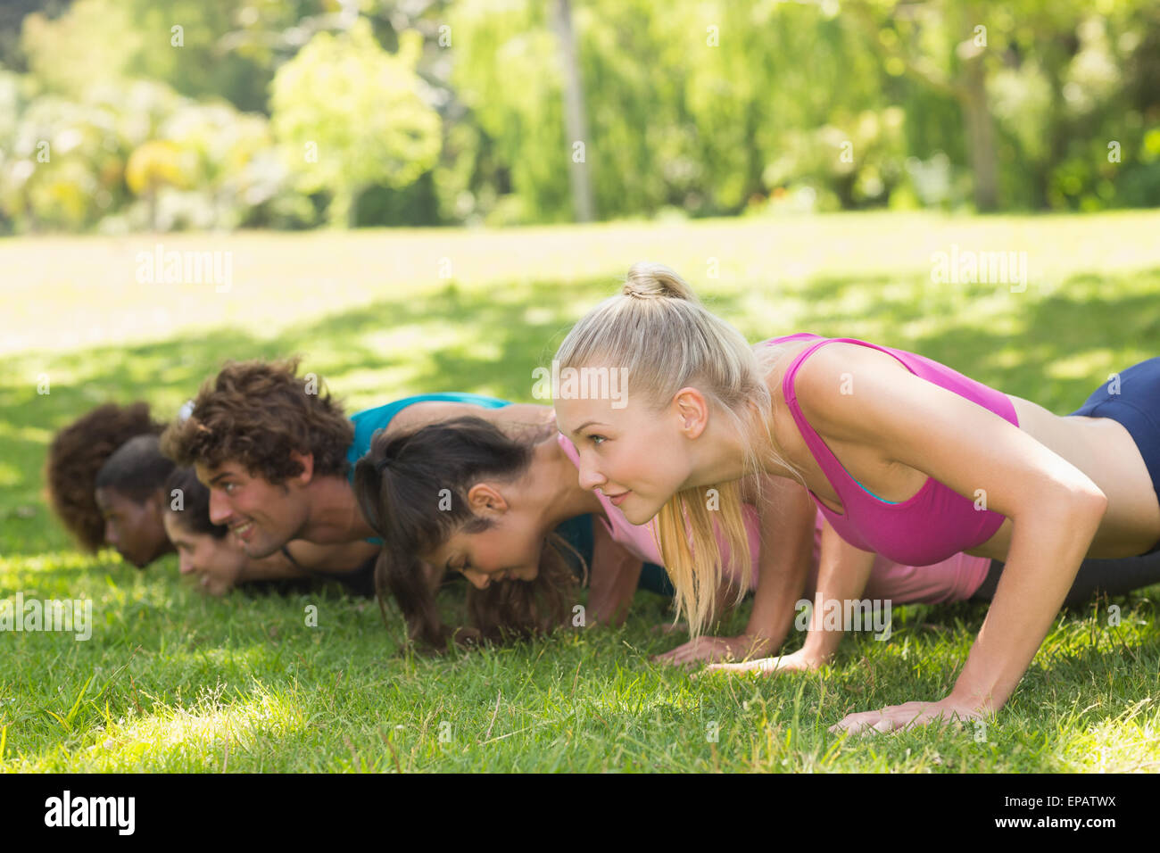Group of fitness people doing push ups in park Stock Photo