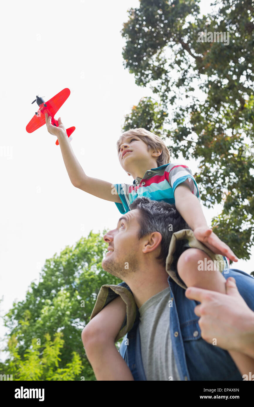 Boy with toy aeroplane sitting on father's shoulders Stock Photo