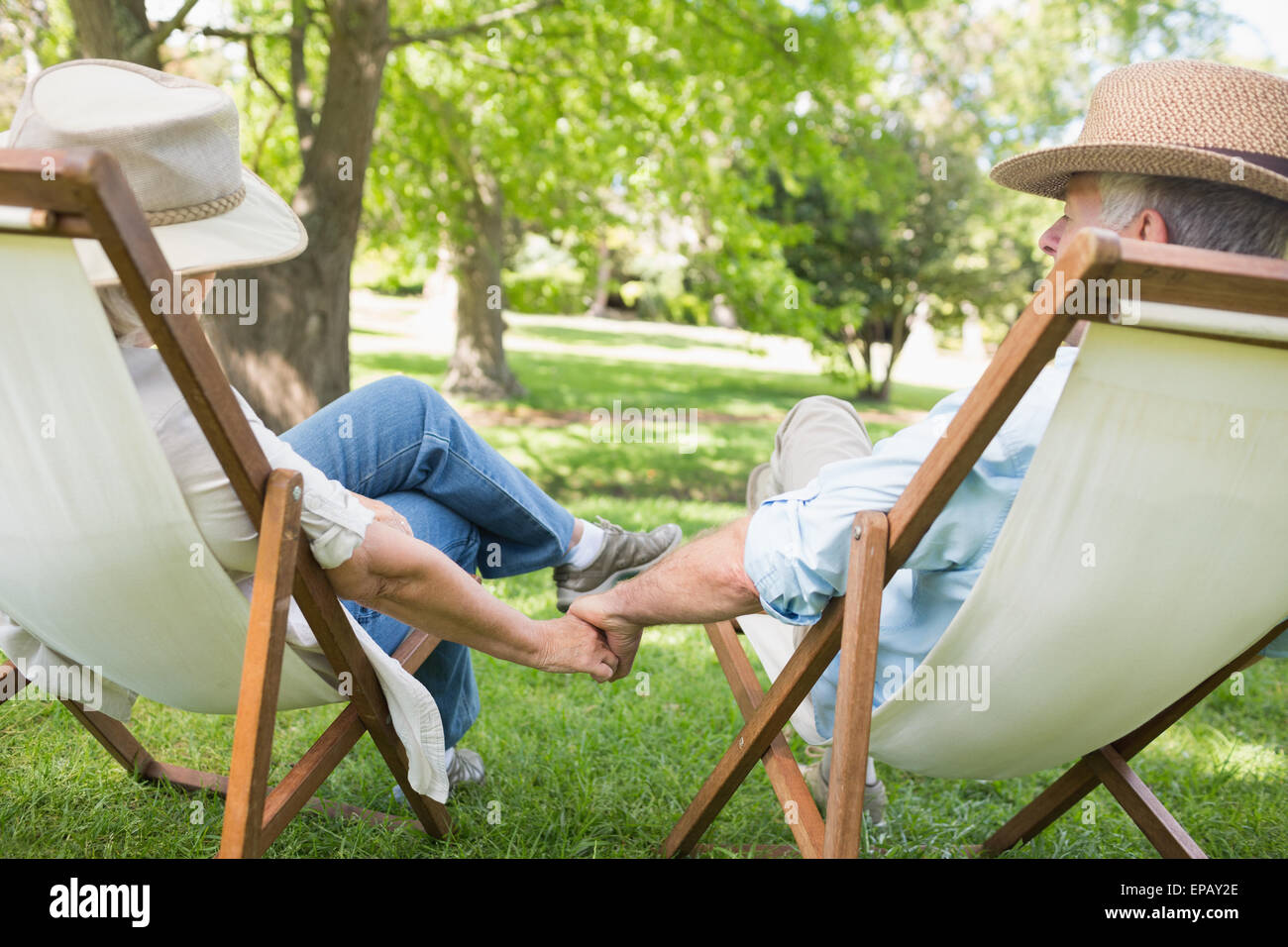 Mature couple sitting in deck chairs at park Stock Photo - Alamy