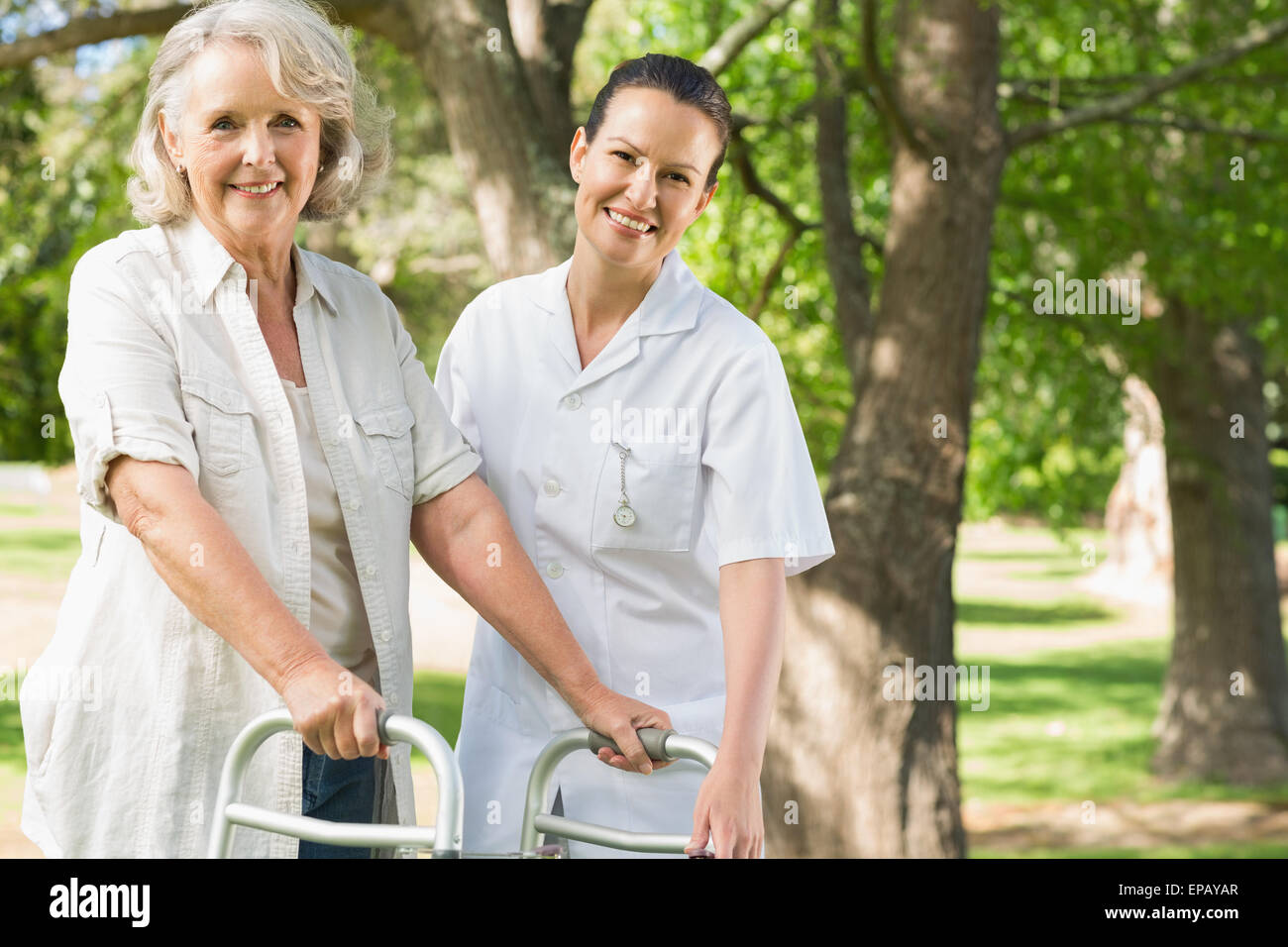 Female assisting mature woman with walker at park Stock Photo - Alamy