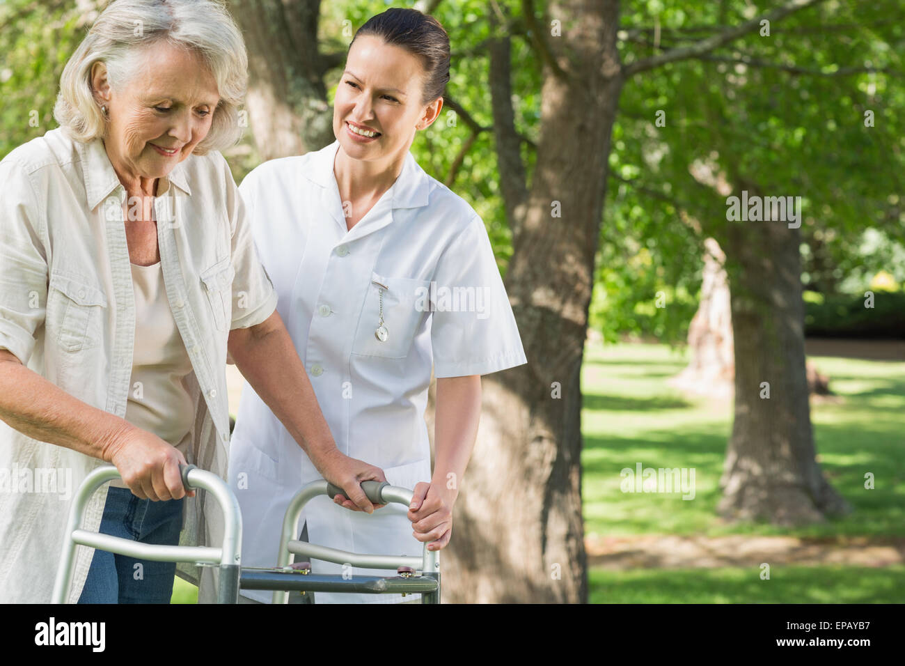 Female assisting mature woman with walker at park Stock Photo - Alamy