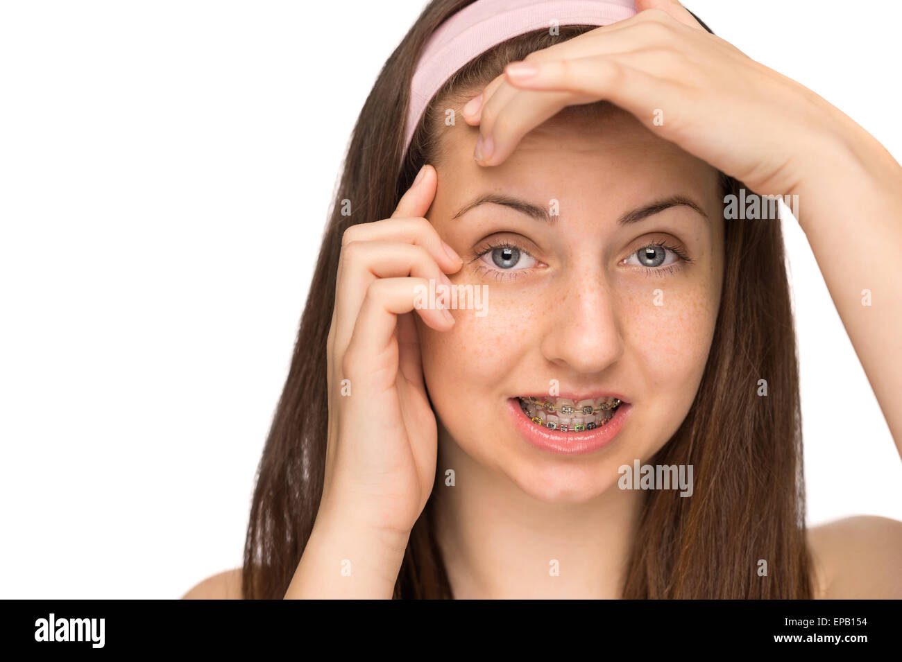 Worried girl with braces squeezing pimple isolated Stock Photo Alamy