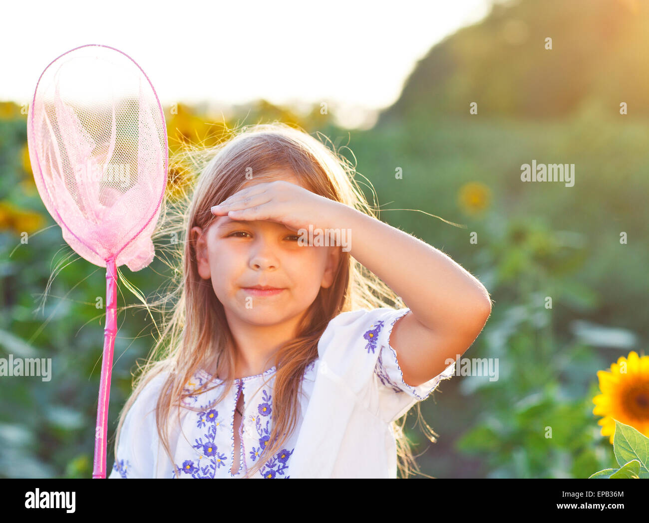 Cheerful little girl playing in a field with insect net Stock Photo Alamy