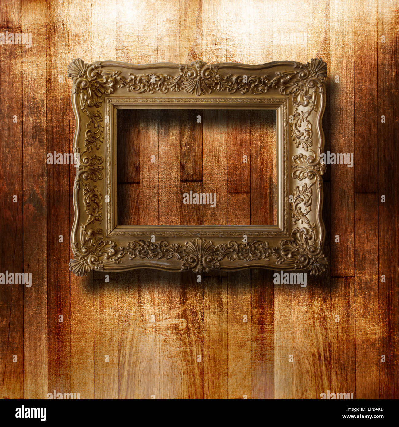 Old gilded picture frame for portrait on the scratched wooden wall