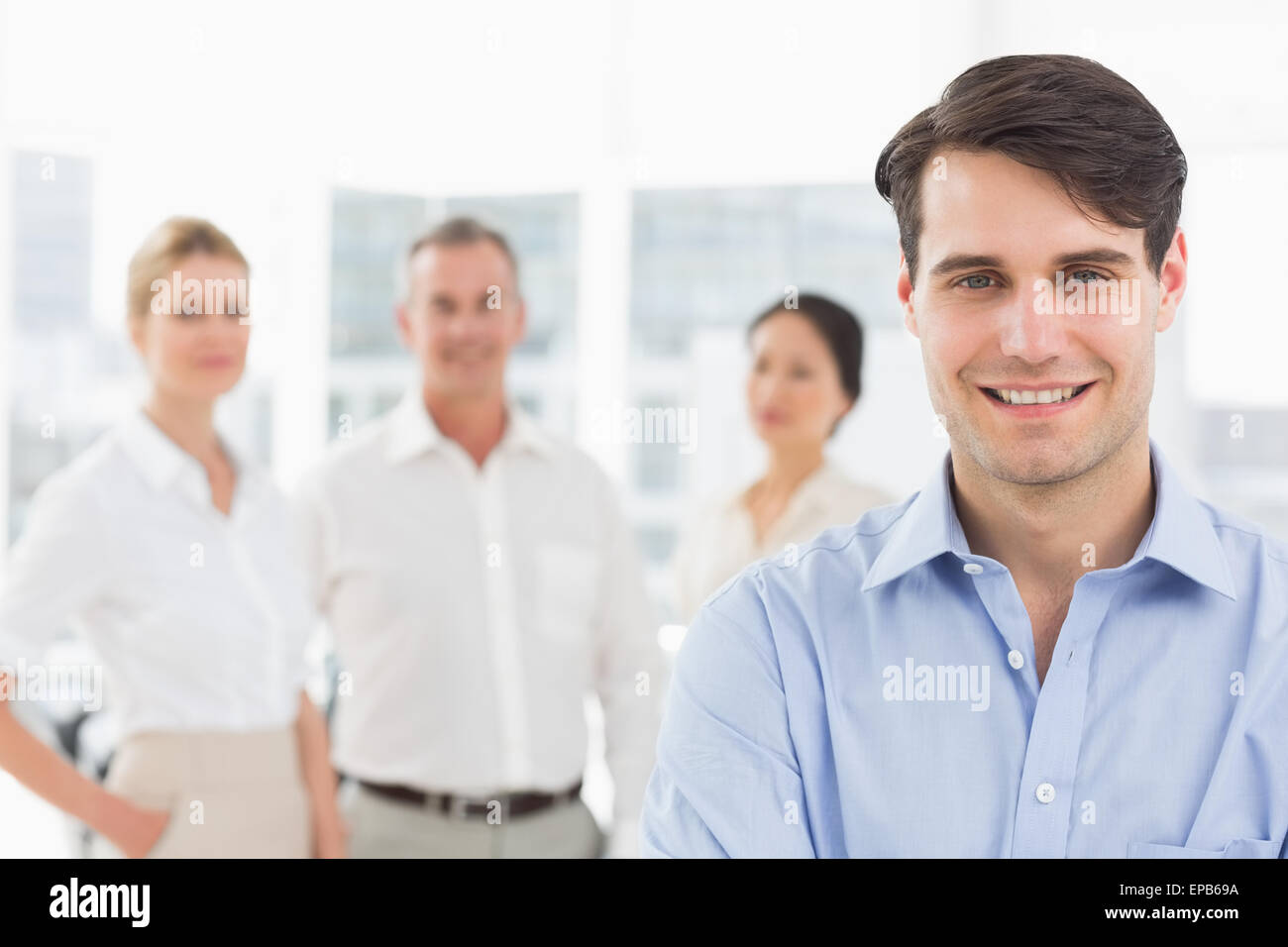 Smiling businessman standing with team behind him Stock Photo - Alamy