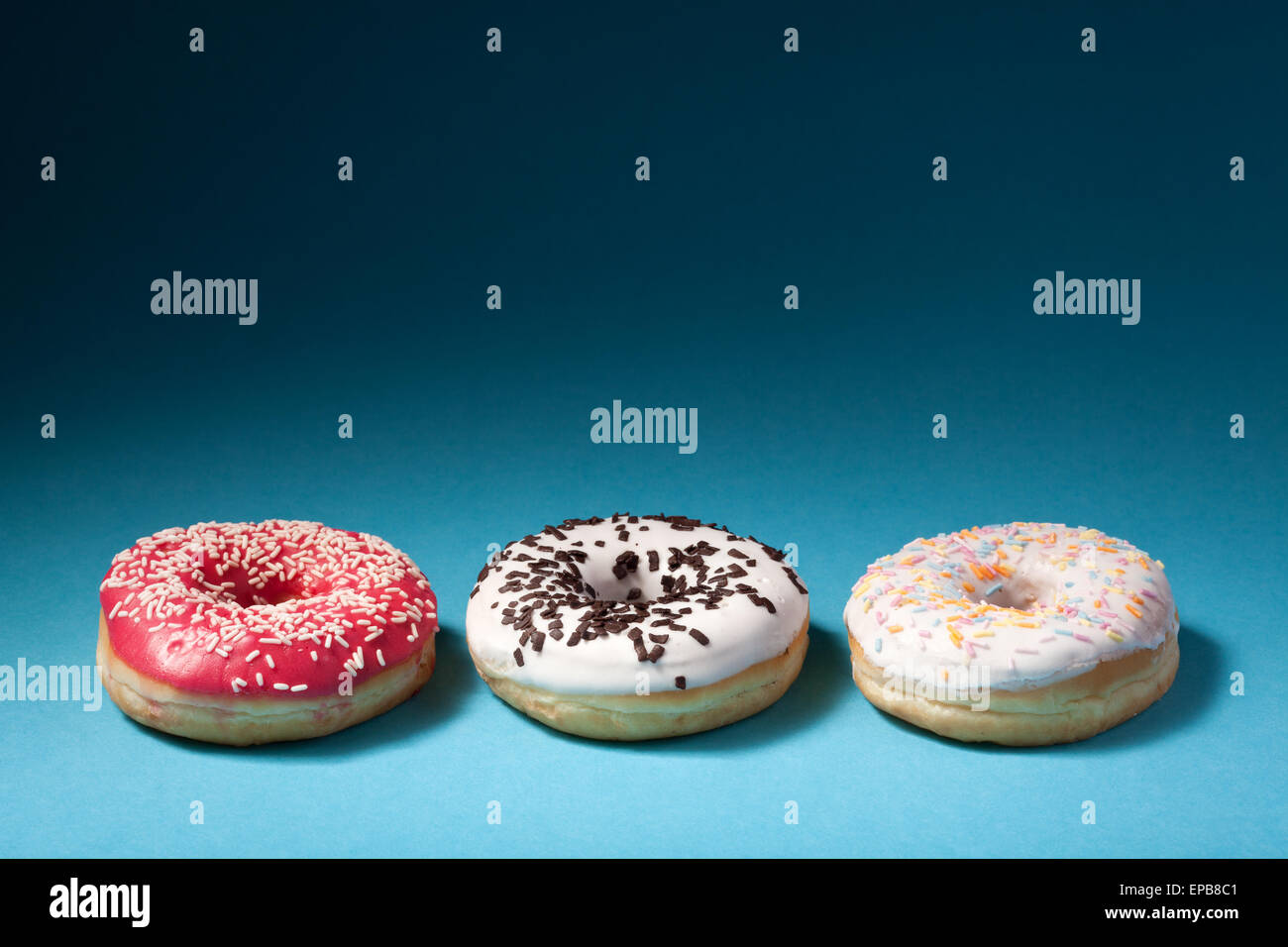 three donuts with color icing isolated on blue Stock Photo Alamy