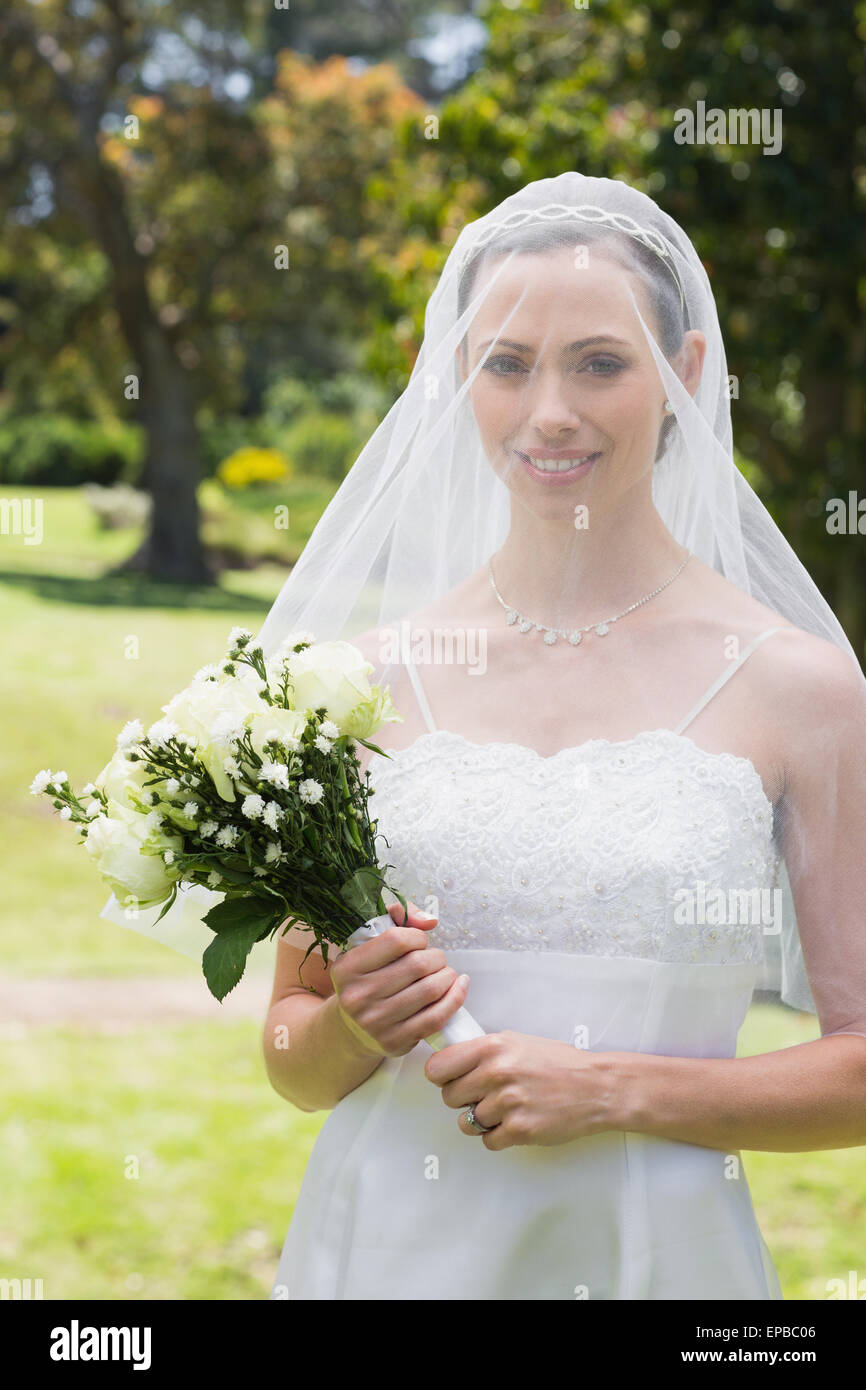 Beautiful bride with flower bouquet wearing veil Stock Photo - Alamy