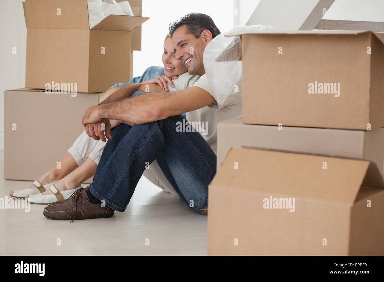 Smiling couple sitting amid boxes in new house Stock Photo - Alamy