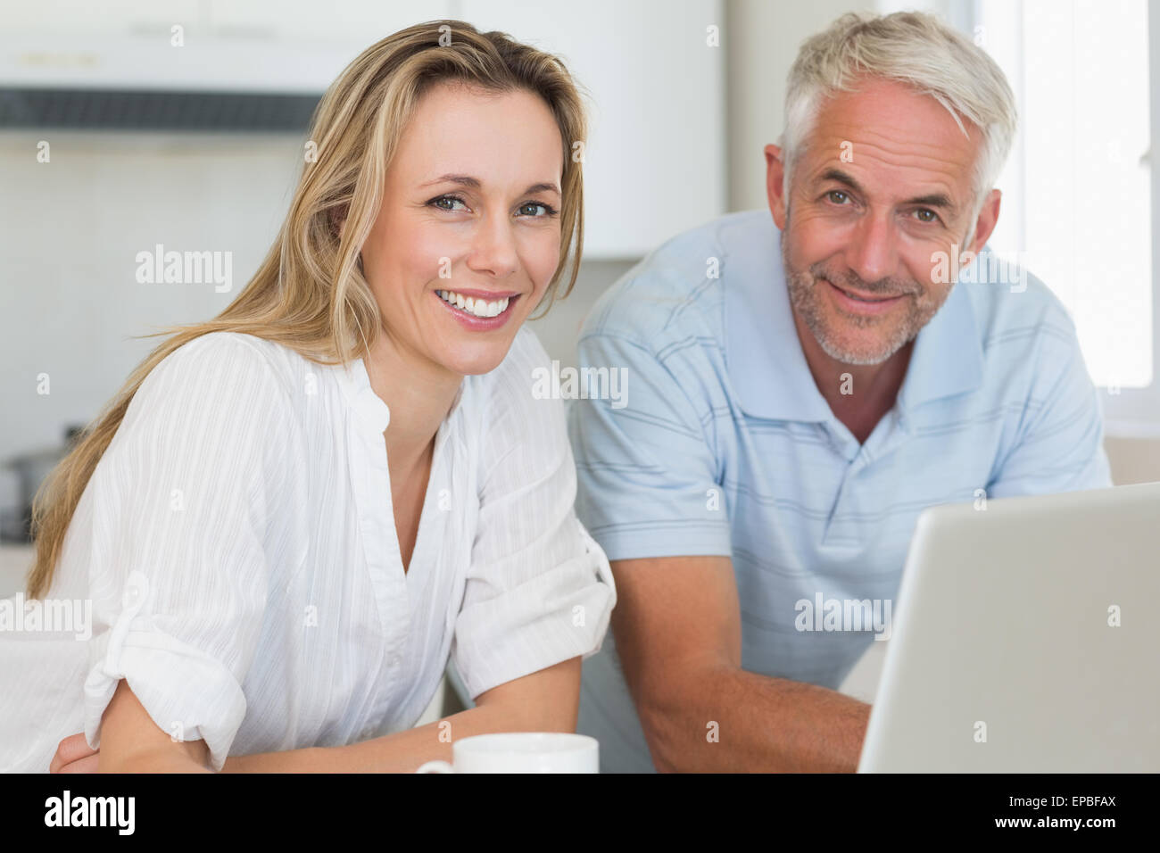 Smiling couple using laptop together at the counter Stock Photo - Alamy