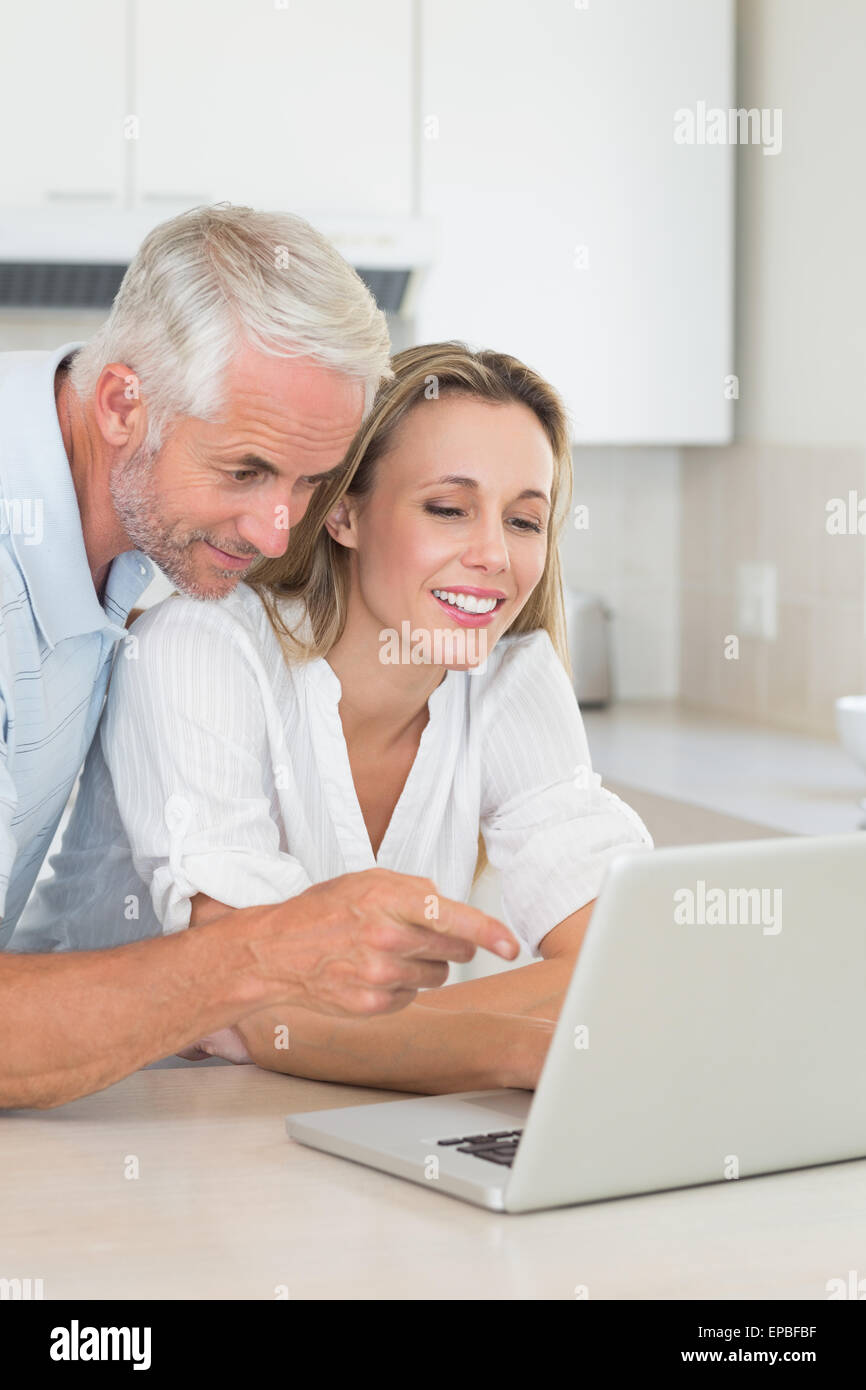 Happy couple using laptop together at the counter Stock Photo - Alamy